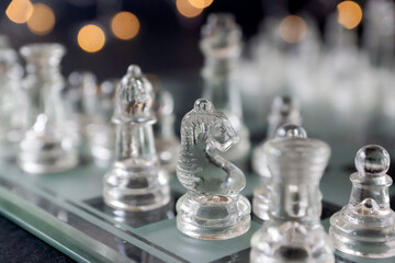 Transparent glass chess pieces on a black table.