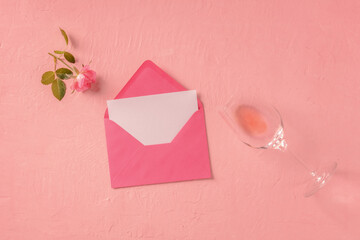 Romantic card or invitation mock up, an overhead flat lay shot with a pink rose and a glass of rose wine, toned image