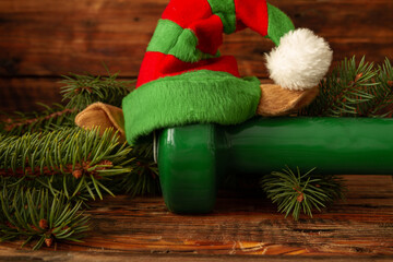 Heavy green dumbbell with elf hat. Exercise equipment as a Christmas gift idea. Healthy fitness...