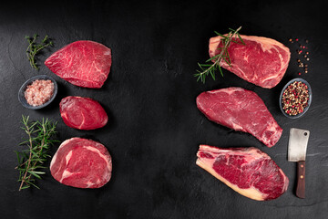 Meat, different cuts, shot from the top on a dark background with condiments and a place for text