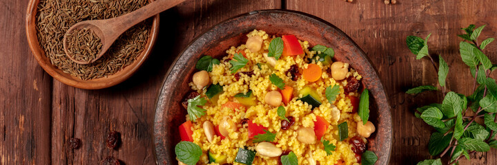 Couscous flat lay panorama on a dark wooden background with ingredients