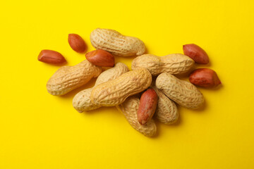 Tasty shelled and unshelled peanut on yellow background