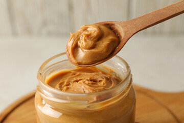 Spoon and jar with peanut butter, close up