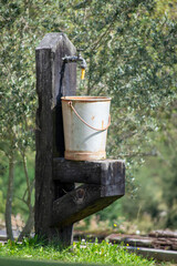 A metal bucket at a wooden fountain
