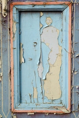 Pieces of old blue cracked paint on the vertical vintage door