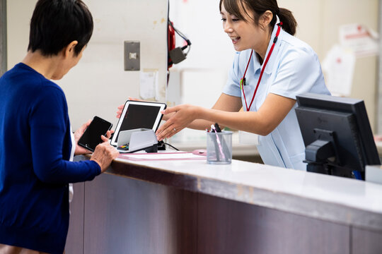 病院代の支払いをスマートフォンで済ませている高齢の女性