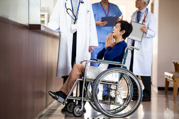 車椅子に乗る高齢女性と医師たち