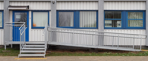 A  metal ramp and stairs for wheelchairs  in a  city school for disabled children