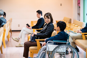 Fototapeta na wymiar 病院の待合室で会話をする車椅子の男の子と母親、独身の青年男性たち