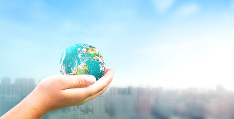Human hand holding earth global over blurred  city background. Elements of this image furnished by NASA