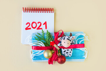 Christmas 2021. Protective mask in form gift with a bow and notepad text 2021. New normal. Xmas holiday background. Pandemic Isolation Lockdown Christmas at home