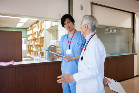 病院の受付前で若手医師とベテラン医師が会話をしている