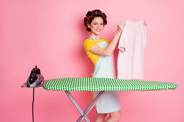 Portrait of positive girl hold t-shirt iron dry board wear dotted dress isolated over pastel color background