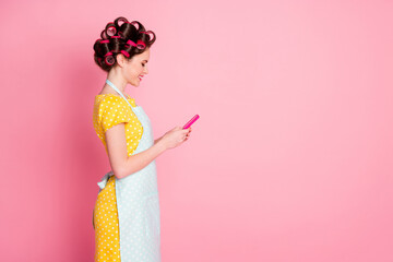 Profile side view portrait of pretty cheerful focused housemaid using gadget share repost isolated on pink pastel color background