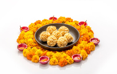 
puffed rice balls in a plate  kept on Rangoli design made with flower petals of rose and marigold  for Diwali celebration in India