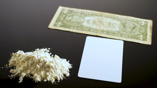 Lines of cocaine and a dollar bill. Cocaine lines shots on a black table glass. Cocaine powder, Credit card, close up, toned. Drug abuse concept. White poder on black table