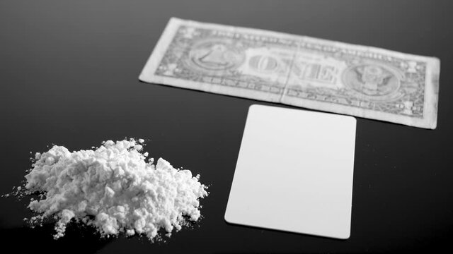 Lines of cocaine and a dollar bill. Cocaine lines shots on a black table glass. Cocaine powder, Credit card, close up, toned. Drug abuse concept. White poder on black table