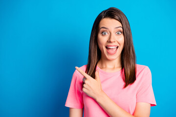 Photo portrait of amazed surprized female student pointing finger at blank space smiling isolated on vibrant blue color background