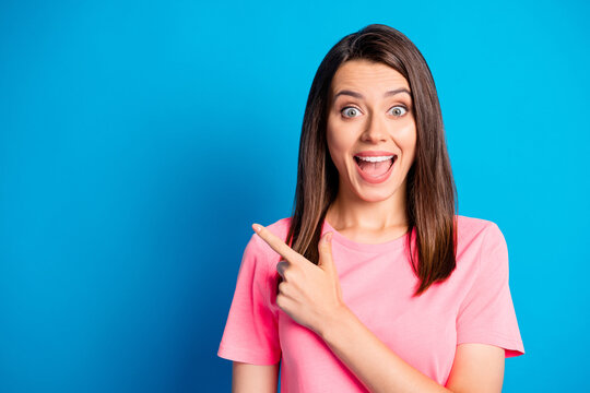 Photo portrait of amazed surprized female student pointing finger at blank space smiling isolated on vibrant blue color background