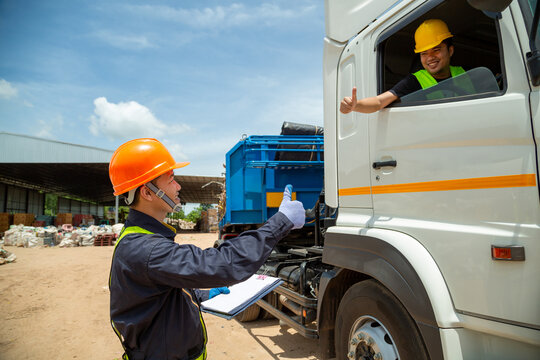 Asian Foreman With Safety Hats And Safety Vest Is Carrying A Car Inspection Document In The Parking With Truck Drivers,Concept Of Planning Work Day. Road Transport Safety Concept