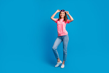 Full length body size photo of pretty happy young woman dancing take-off sunglass isolated on vibrant blue color background