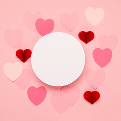 Pink, red paper hearts and empty frame on pastel pink background. Valentines day concept.