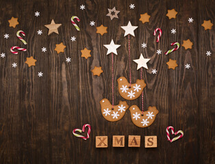 Christmas holiday background with homemade gingerbread cookies, candy canes, snowflakes on dark wooden table.