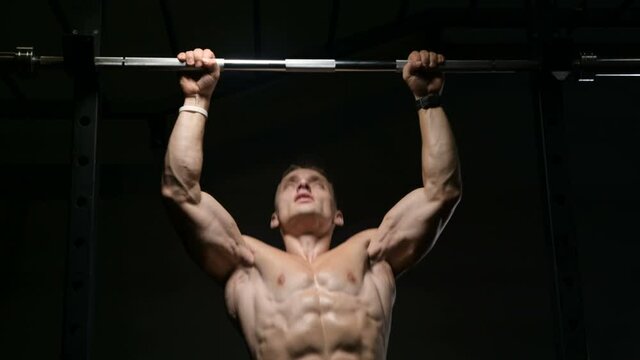 Fitness man pumping up muscle doing pull-ups exercises in gym naked torso. Handsome strong athletic men pumping up back muscles workout fitness and bodybuilding concept background