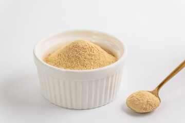 Lecithin powder in a bowl with a spoon on a white background.