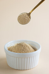 Lecithin in a spoon with a bowl on a beige background.