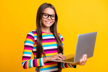 Photo portrait of happy clever schoolgirl browsing internet on laptop smiling cheerfully isolated...