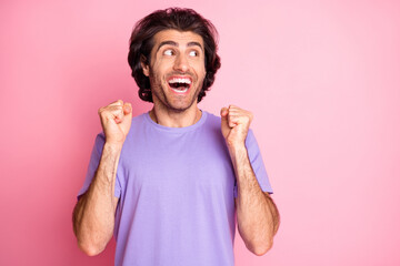 Photo of excited man raise fists look empty space open mouth wear violet t-shirt isolated pastel pink color background