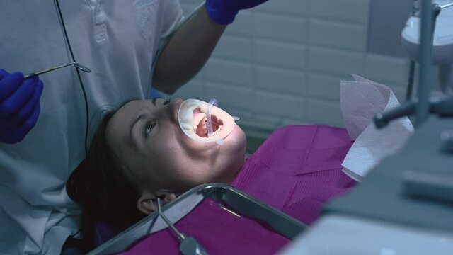 The dentist conducts oral hygiene to the patient with ultrasound.2020