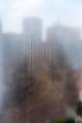 Foggy Window with condensate or steam after heavy rain, large texture or background. Wet misted glass, blurred cityscape in the background