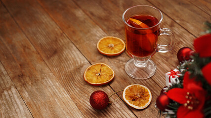Christmas mulled wine in glass cup on a wooden table with dry oranges