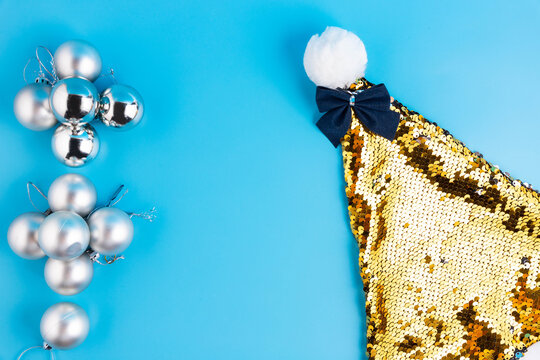 Christmas Gold Santa Hat On A Blue Background And Silver Balls. A Place For Congratulations.