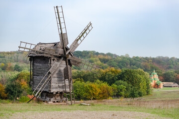 Fototapeta na wymiar Beautiful autumn view of old wooden windmill in countryside. Ukrainian village.