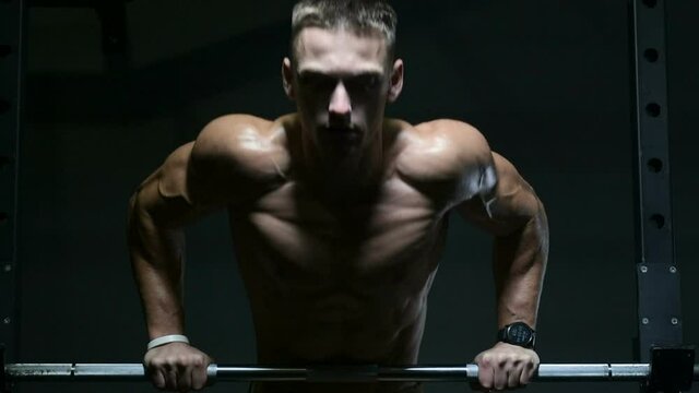 Fitness man doing push ups in gym. Strong bodybuilder with six pack doing exercise for chest and shoulders in gym. Fitness, bodybuilding and workout concept