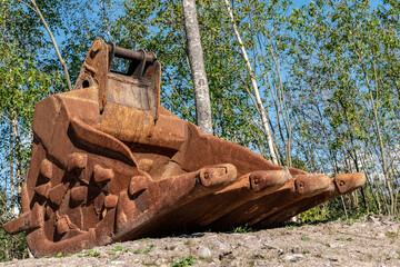 A large abandoned excavator in a park area in Helsinki.