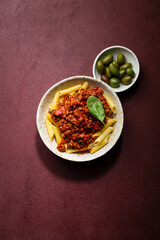 Overhead view of bolognese pasta on red background