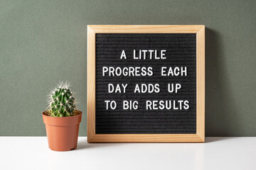 A little progress each day adds up to big results. Motivational quote on letter board, cactus,...