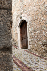 Fototapeta na wymiar Old wooden door on wall made of stone.