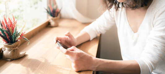 Close up hands of woman using smartphone watching video clip and playing online game. Technology business and social distancing concept. Panoramic banner portion