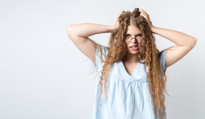 Fototapeta premium Photo of girl looking at the camera, astonished, holding hands on head. Problems, surprise, fear, fobia concept