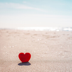 Romantic symbol of red heart on the sand beach