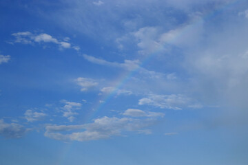 A rainbow of light colors occurs in the cloudy sky.