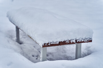 The lonely bench is covered with snow.