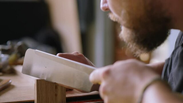 a bearded joiner carves a dovetail joint on an oak board with a Japanese hand saw for wood.handmade carpentry. the sound of carpentry tools