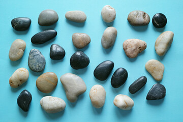 青い紙の背景に置いた複数の小石。平置きの俯瞰撮影。