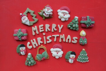 Creative Merry Christmas, with wooden letters and marzipan Christmas symbols over red color background